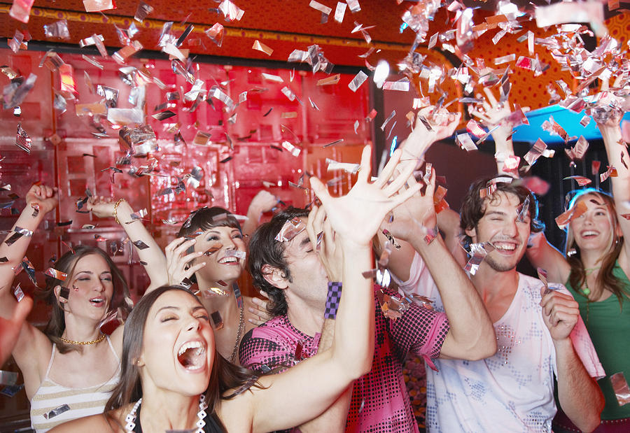 Group of people in a nightclub partying and throwing confetti Photograph by Paul Bradbury