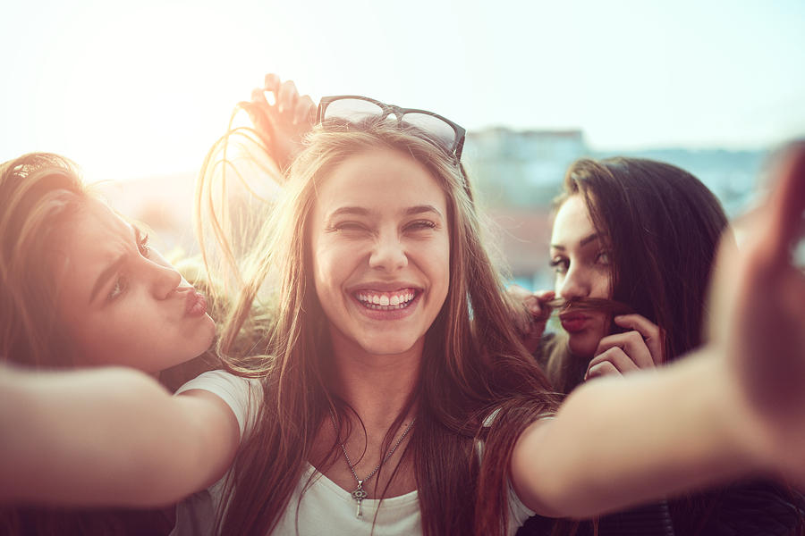Group of Smiling Girls Taking Funny Selfie Outdoors at Sunset Photograph by AleksandarGeorgiev