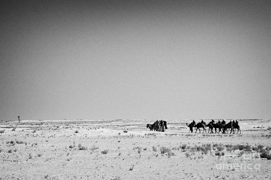 group of tourists in the distance on camels walking through the sahara ...