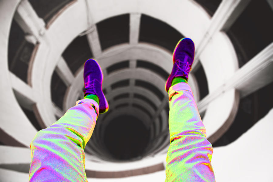 Guy from personal perspective taking a picture with legs over of a beautiful spiral geometric shape created by a parking ramp in a decay architecture building with nice vanishing point and vertigo feeling. Photograph by Artur Debat