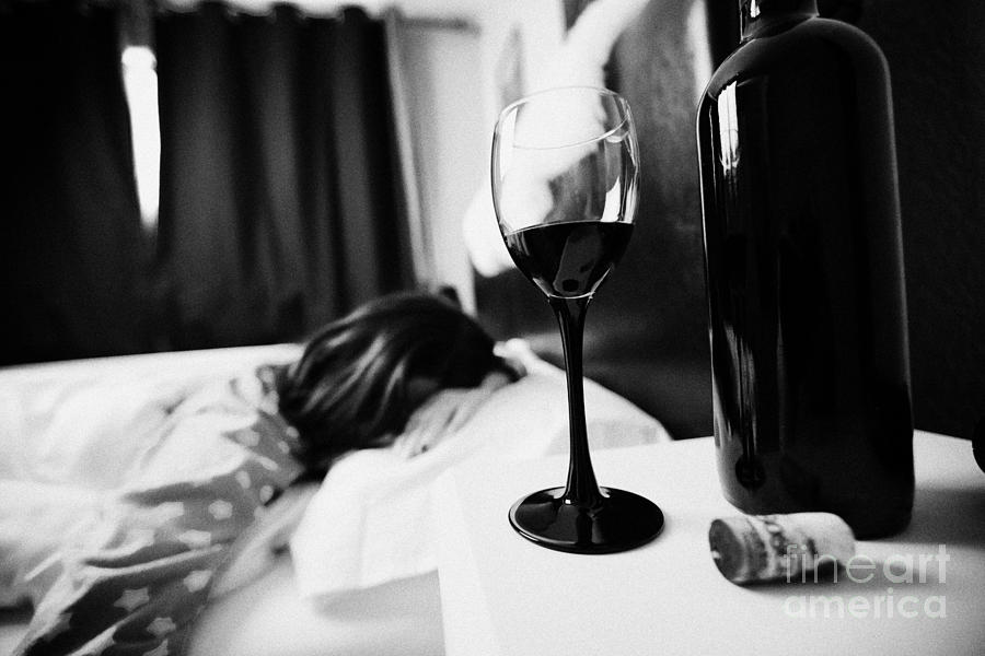 Wine Photograph - Half Full Glass Of Wine On Bedside Table Of Early Twenties Woman In Bed In A Bedroom by Joe Fox