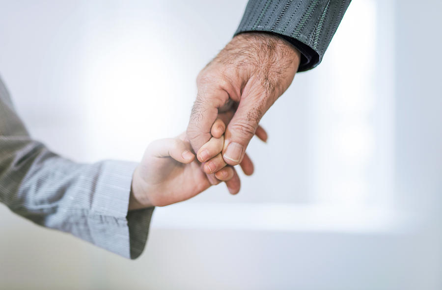 Hand close-up of grandfather and granddaughter holding hands. Photograph by DjelicS