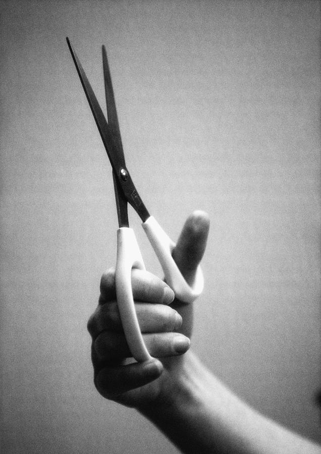 Hand holding scissors, close-up, b&w Photograph by Laurent Hamels