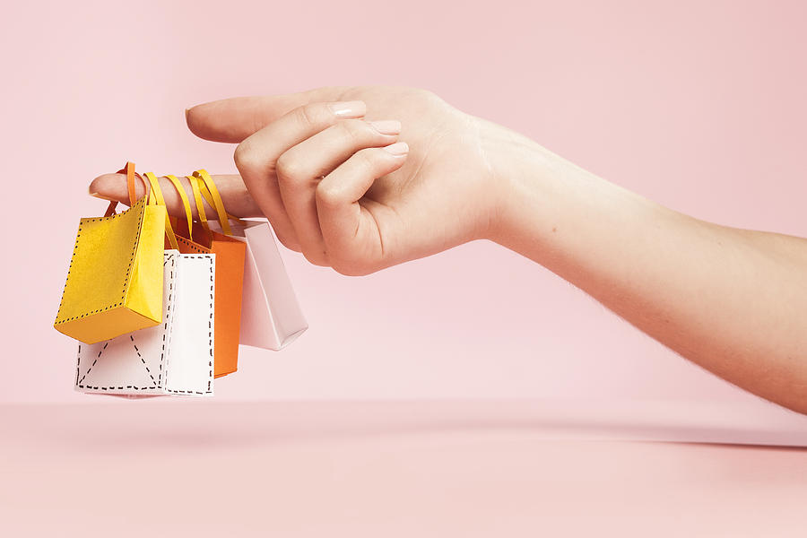 Hand Holding Tiny Shopping Bags On Plain Pink Photograph by Paper Boat Creative
