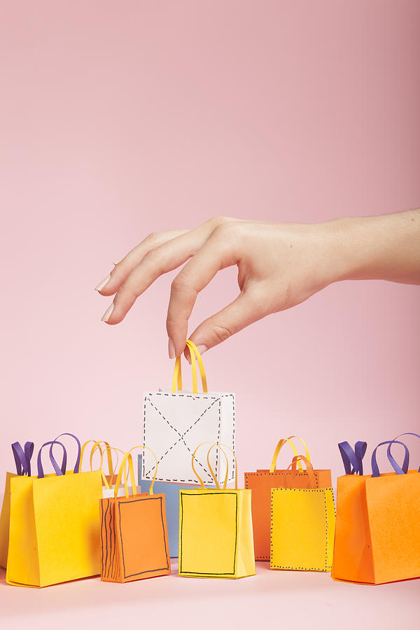 Hand picking up white tiny paper shopping bag Photograph by Paper Boat Creative