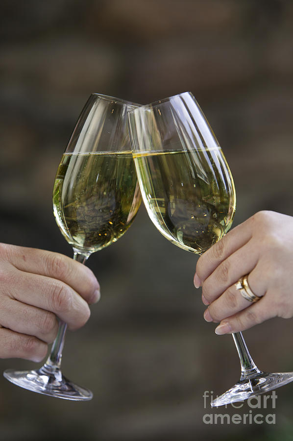 Hands Clinking Two Glasses Of White Wine. Photograph