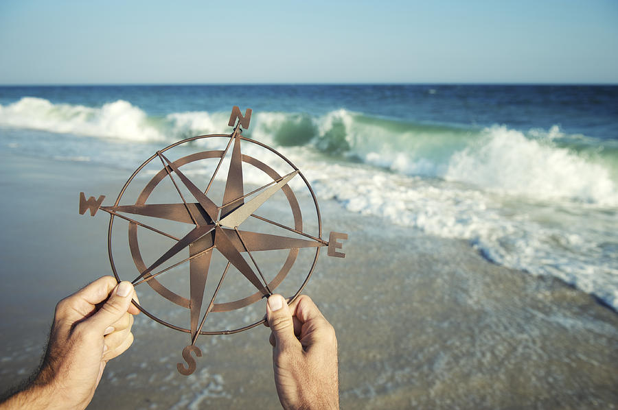 Hands Holding Compass by Sea with Crashing Waves Photograph by PeskyMonkey