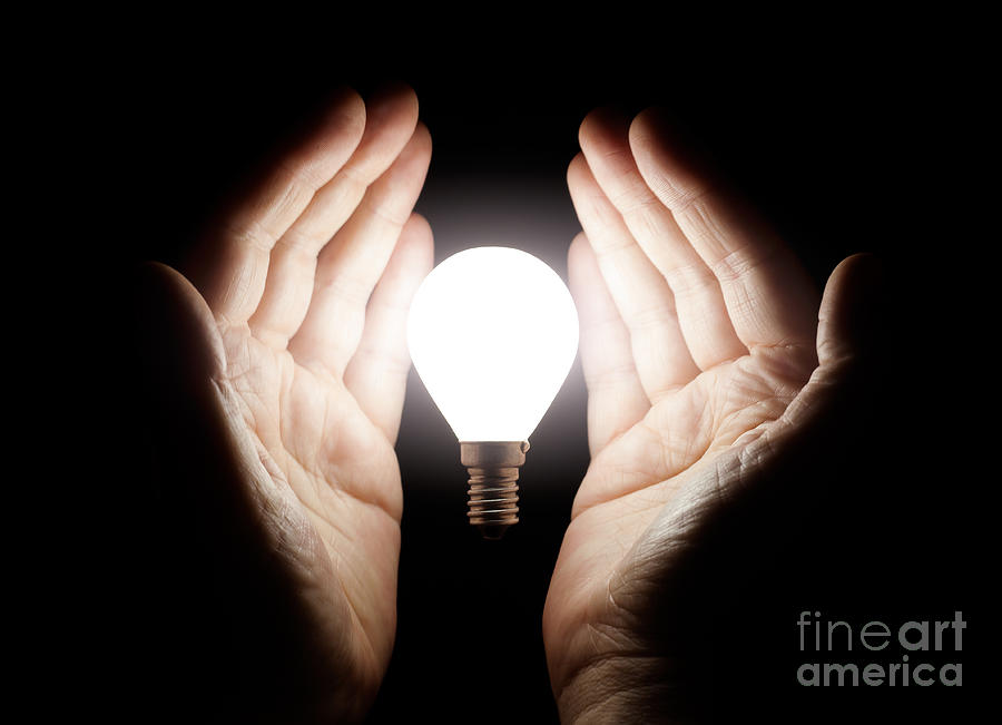 Hands holding light bulb Photograph by Simon Bratt