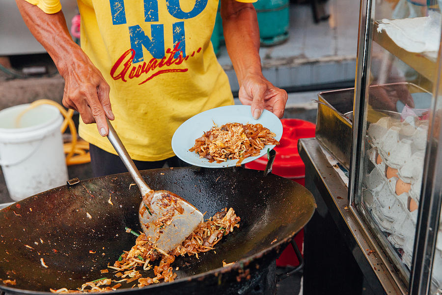 Hands of the senior man cooking kway teow noodles at the street market, Penang, Malaysia Photograph by Elena Aleksandrovna Ermakova