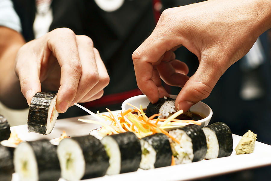 Hands sharing a sushi platter in Asian restaurant Photograph by Clicknique