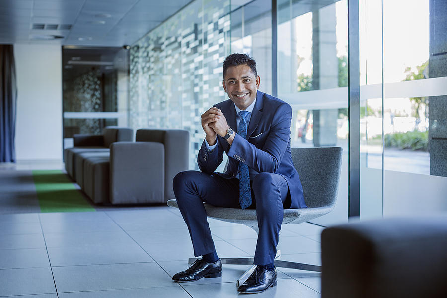 Happy businessman sitting in office lobby Photograph by Morsa Images Happy businessman sitting in office lobby Photograph by Morsa Images