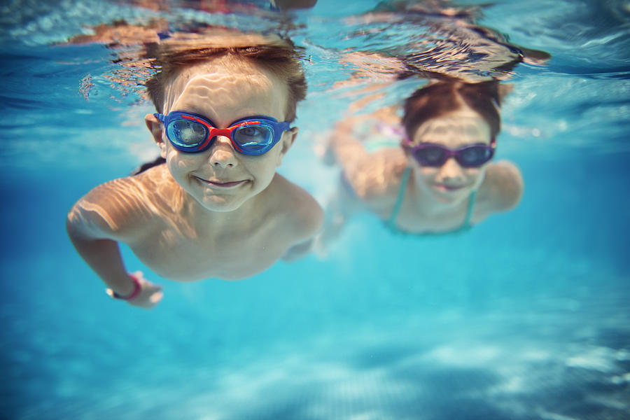 Happy kids swimming underwater in pool Photograph by Imgorthand