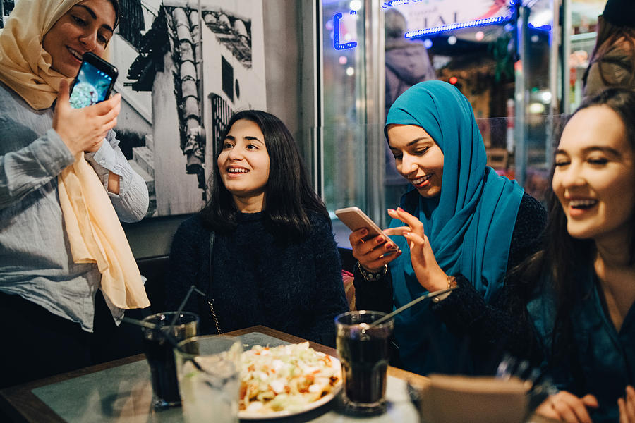 Happy multi-ethnic female friends enjoying at cafe Photograph by Maskot