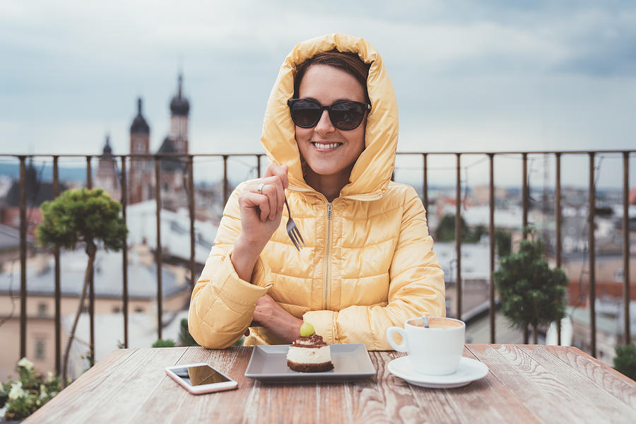Happy woman eating dessert with coffee on rooftop Photograph by Martin-dm