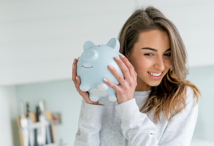 Happy woman saving money in a piggybank Photograph by Andresr