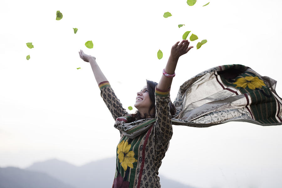 Happy young woman flying leafs in air towards sky. Photograph by Gawrav