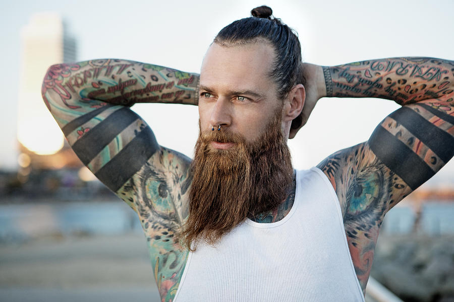 Heavily tattooed bearded athletic alternative man stretching before a workout Photograph by Lorado