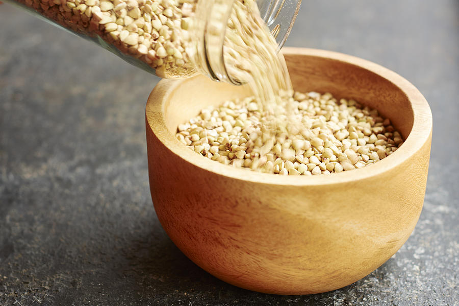Hemp seeds being poured into a wooden bowl Photograph by Westend61