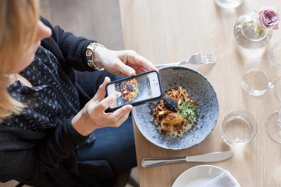 High angle view of woman photographing food through mobile phone in restaurant Photograph by Apeloga AB