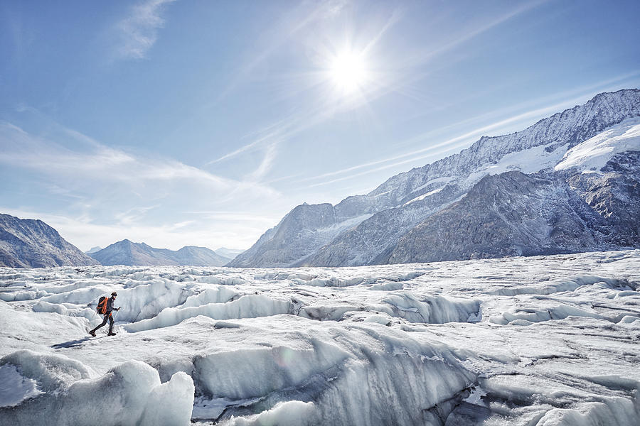 Hiker on glacier with distant mountains, Aletsch Glacier, Switzerland Photograph by James ONeil