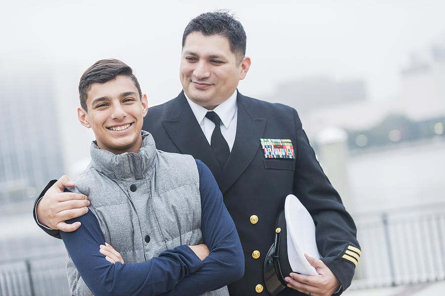 Hispanic naval officer standing with teenage son Photograph by Kali9