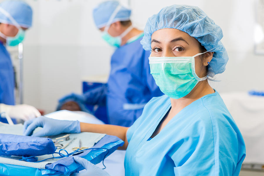 Hispanic surgical nurse or technician assisting with surgery in hospital Photograph by SDI Productions