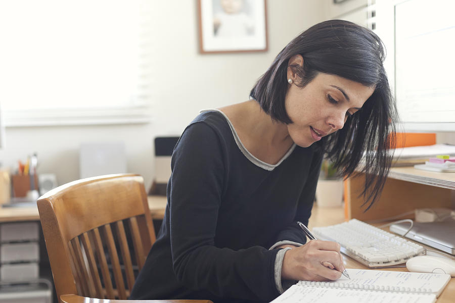 Hispanic woman working in home office Photograph by Pacific Images LLC