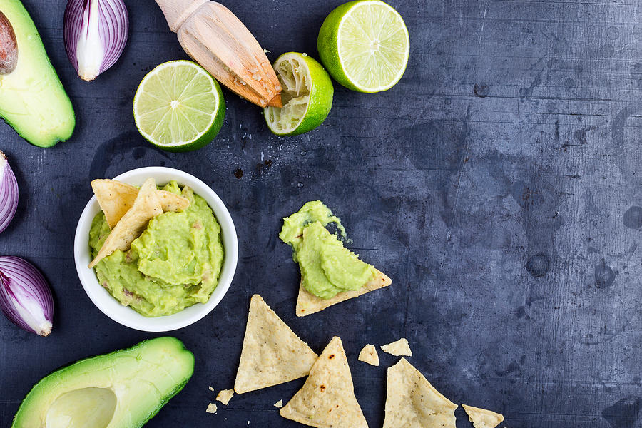 Homemade avocado guacamole dip with fresh ingredients on gark grey background with copy space Photograph by Istetiana