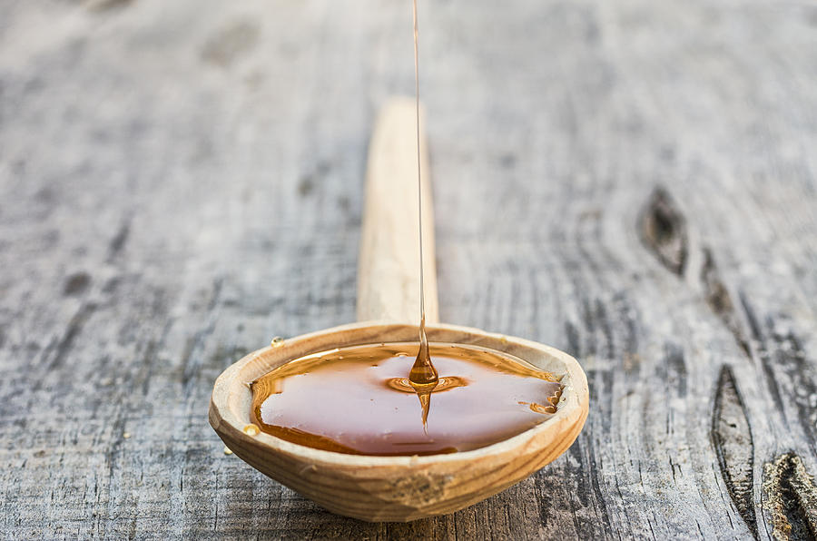Honey in a wooden spoon Photograph by Paulo Goncalves