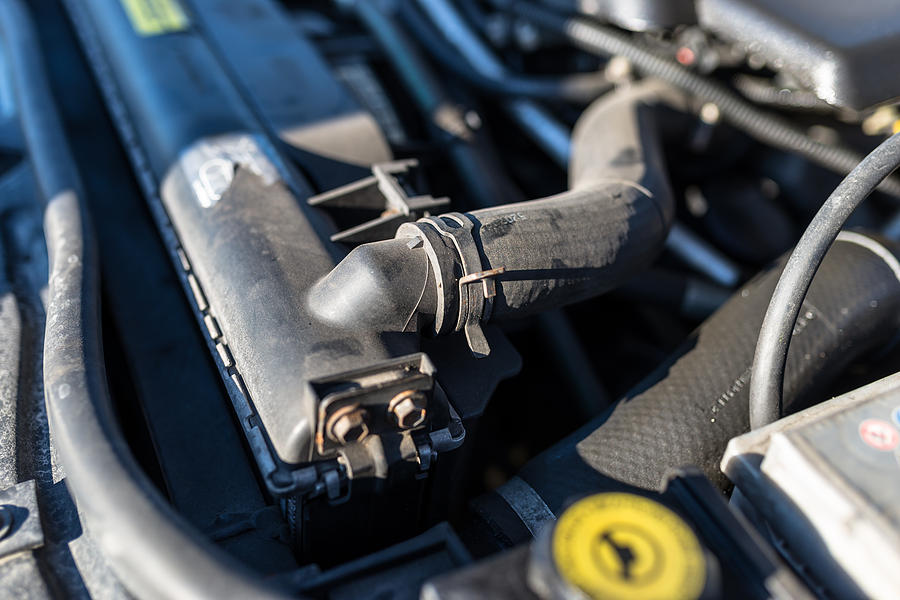 Hose connecting the car radiator with the engine, In the background the engine compartment. Photograph by Kinek00