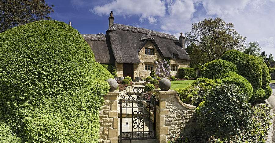 Idyllic country cottage thatched roof pretty summer gardens Cotswolds UK Photograph by fotoVoyager