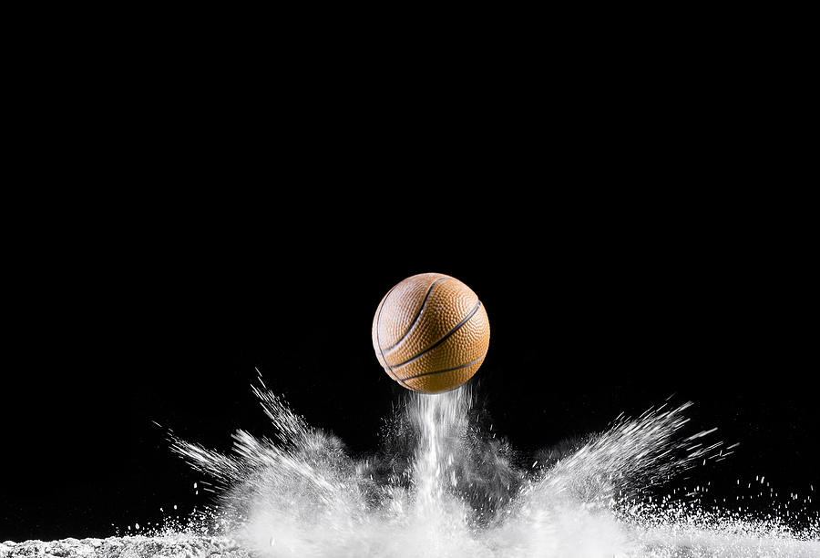 Impact and rebound of a ball of basketball on a surface of land and powder on a black background Photograph by Jose A. Bernat Bacete