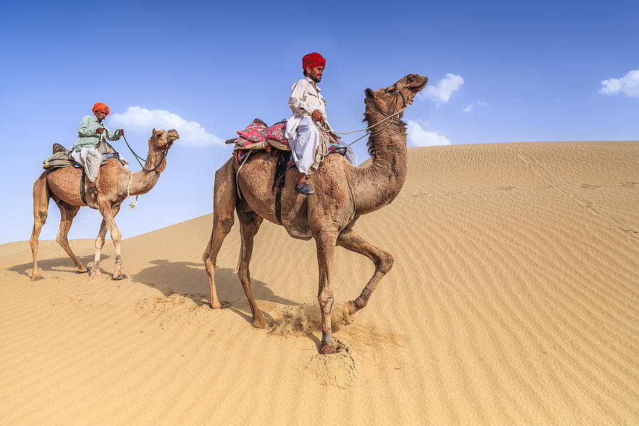 Indian men riding camels on sand dunes, Rajasthan, India Photograph by Bartosz Hadyniak
