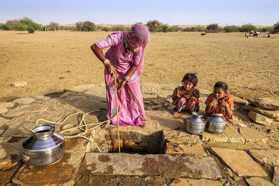 Indian woman drawing water from the well, desert, Rajasthan Photograph by Hadynyah
