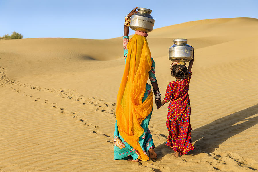 Indian woman with little daughter carrying water from well Photograph by Hadynyah