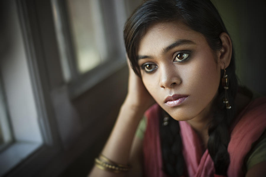 Indoor close-up of serene Asian teenager girl sitting near window. Photograph by Gawrav