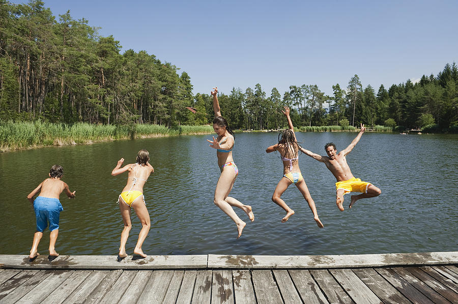 Italy, South Tyrol, Family jumping into lake Photograph by Westend61