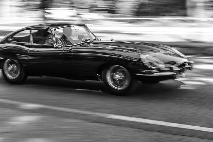 Jaguar E-Type driving at high speed on a road through a forest Photograph by Sjo