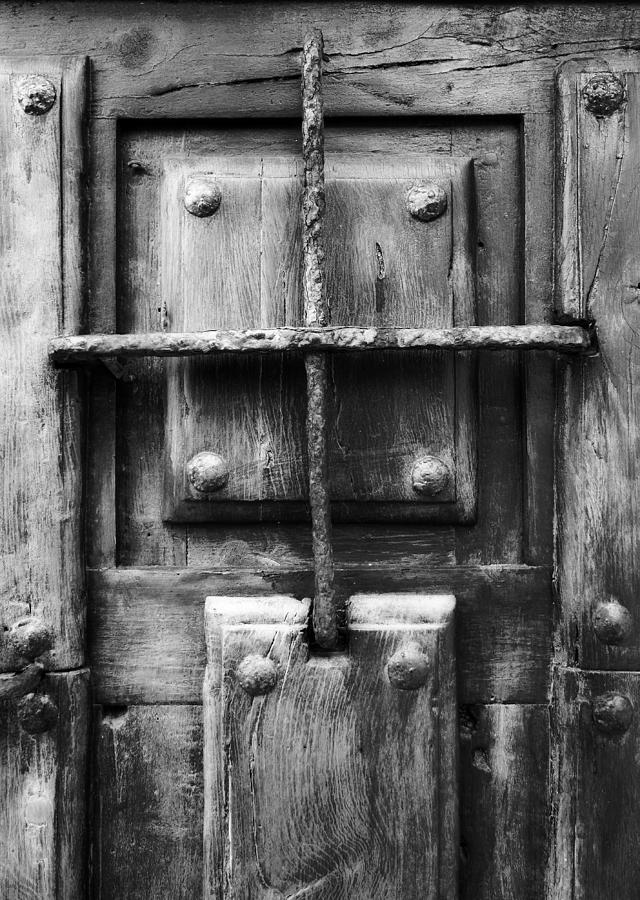 Architecture Photograph - Vintage solid wood door with metal nails and metal grille - Jail of my life bw version by Pedro Cardona Llambias