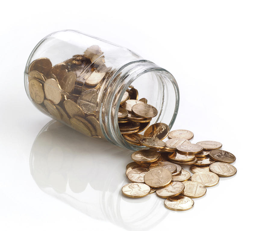 Jar of polished US pennies spilling out on white Photograph by FreezeFrameStudio