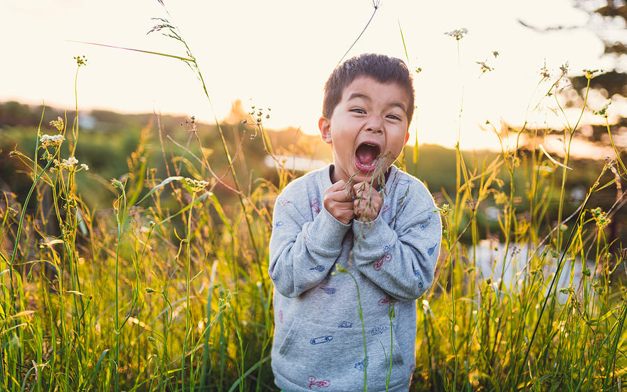 Kid making funny faces outdoor in lush meadow. Photograph by Nazar Abbas Photography