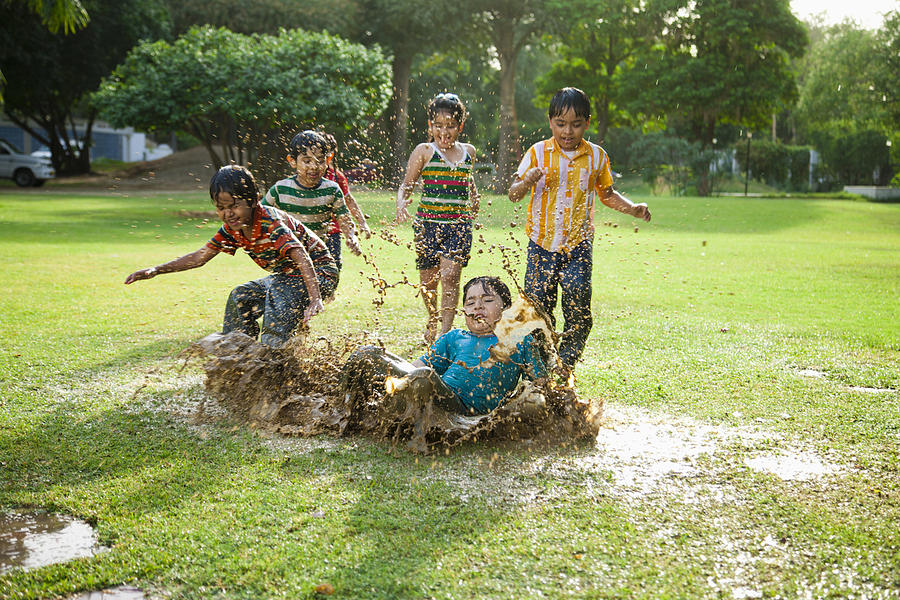 Kids (4-7) playing in puddle of water Photograph by ImagesBazaar