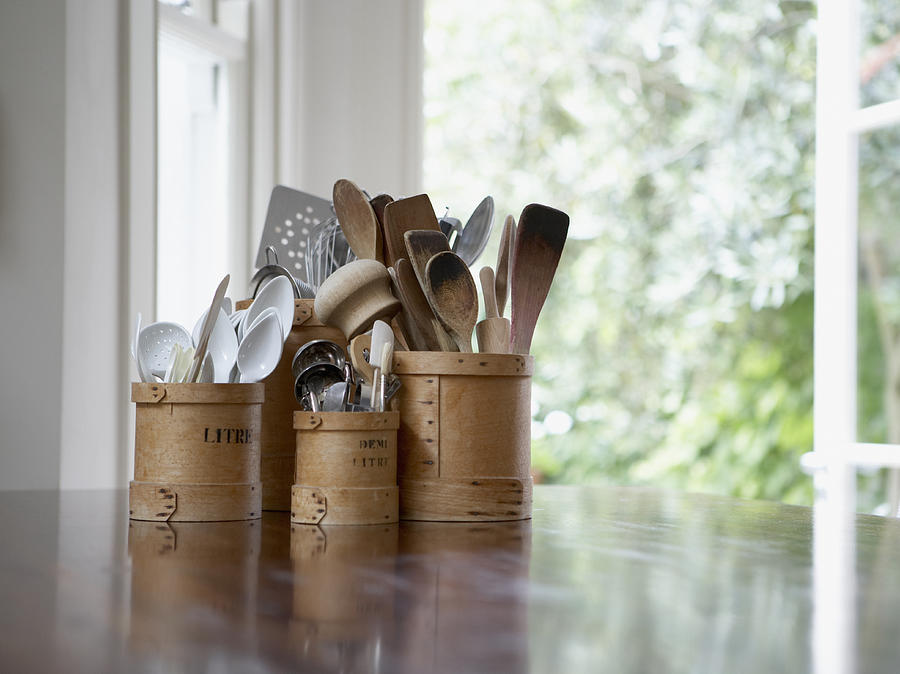 Kitchen utensils in containers on table Photograph by Martin Barraud