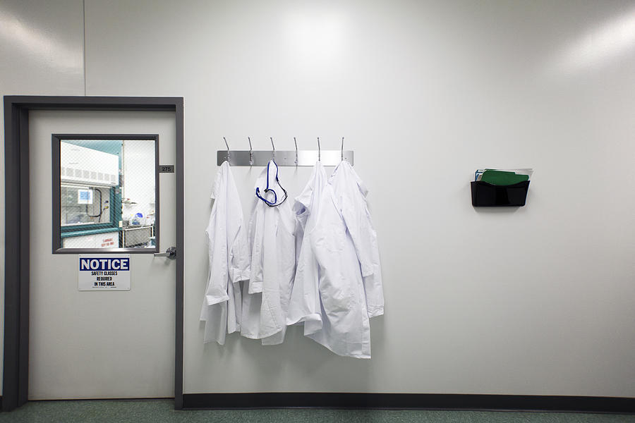 Lab coats on hanger Photograph by Cavan Images