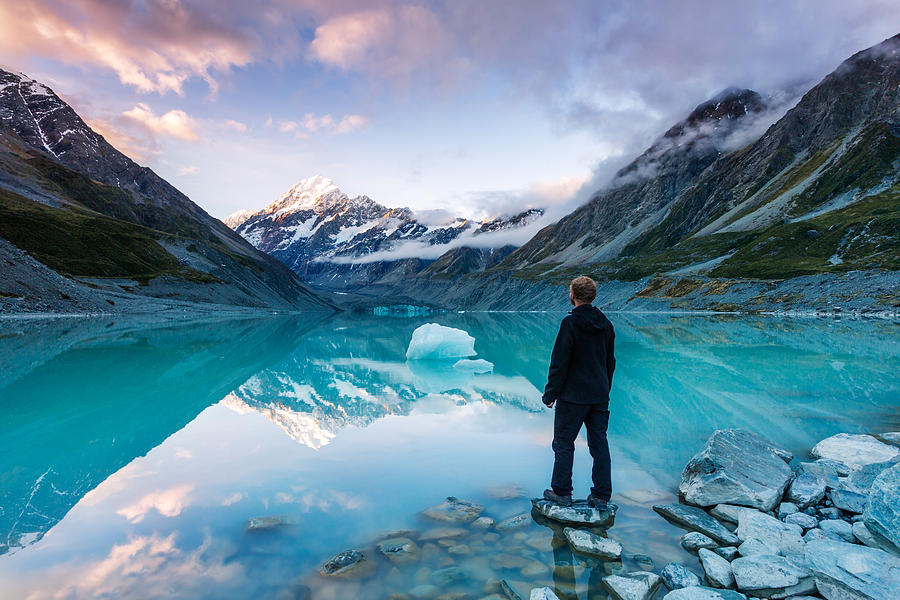 Landscape: hiker looking at Mt Cook from lake with iceberg, New Zealand Photograph by Matteo Colombo