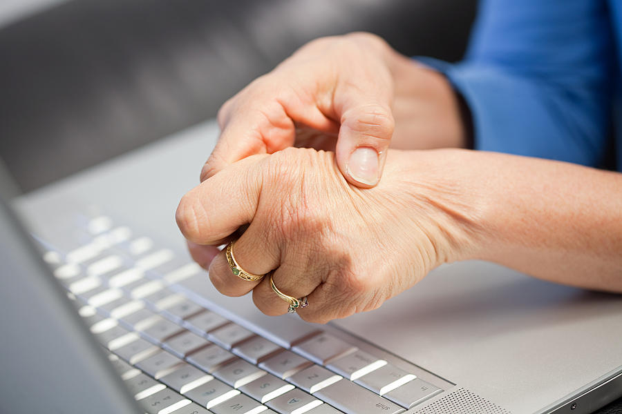 Laptop and woman with pain in hand Photograph by Image Source
