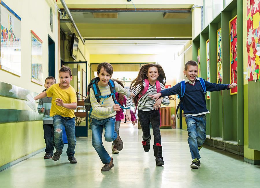 Large group of happy school children running in the hall. Photograph by BraunS