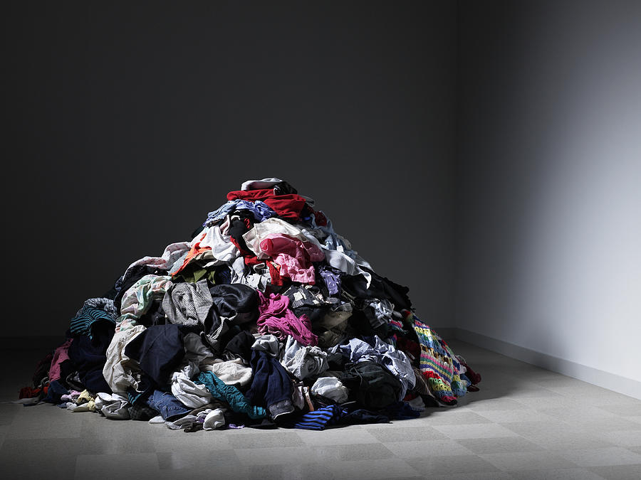 Large pile of clothes in an empty room. Photograph by Ryan McVay