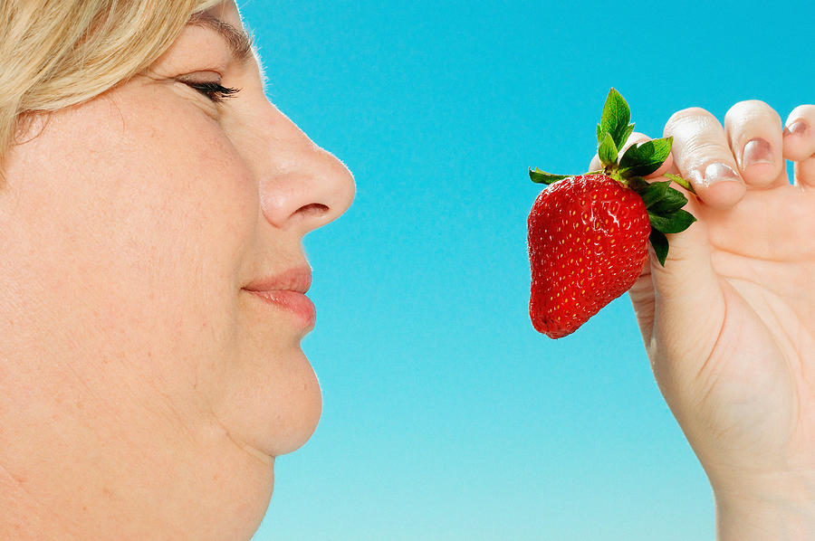 Large woman looking at strawberry Photograph by Image Source