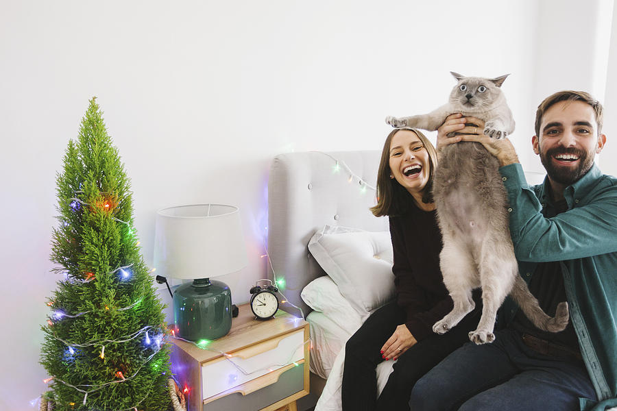 Laughing couple with their cat at home Photograph by Westend61